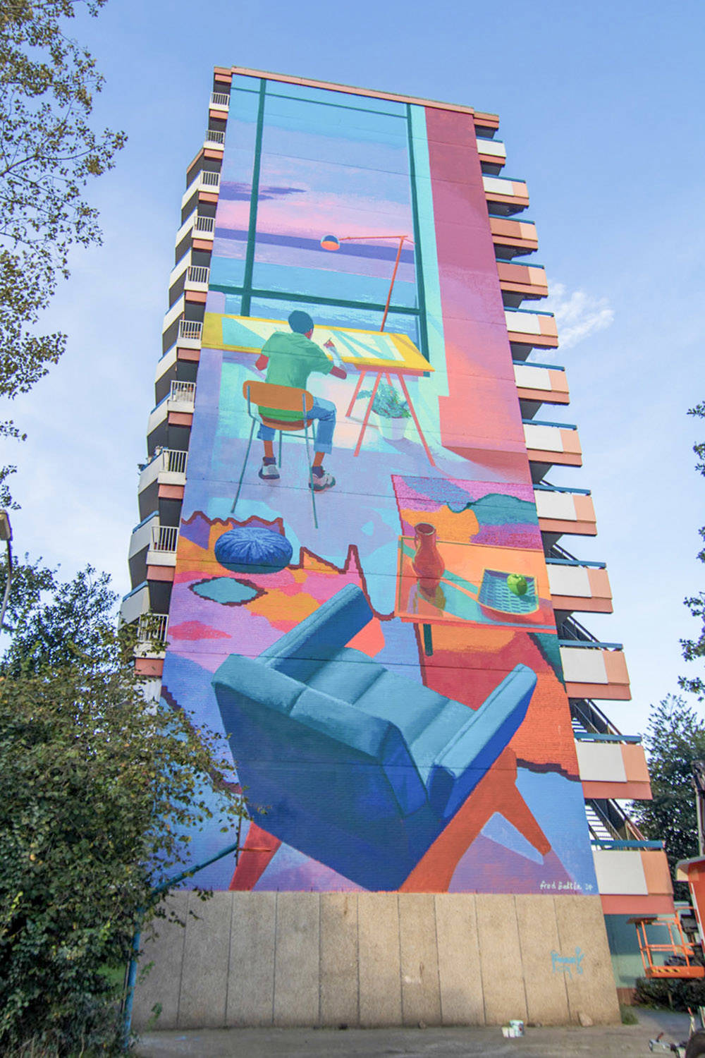 Fred Battle liet zich inspireren door het Kröller Müller Museum voor deze grote, kleurrijke mural van een man aan zijn bureau met uitzicht op zee. Hij is geschilderd aan de zijkant van een groot flatgebouw.
