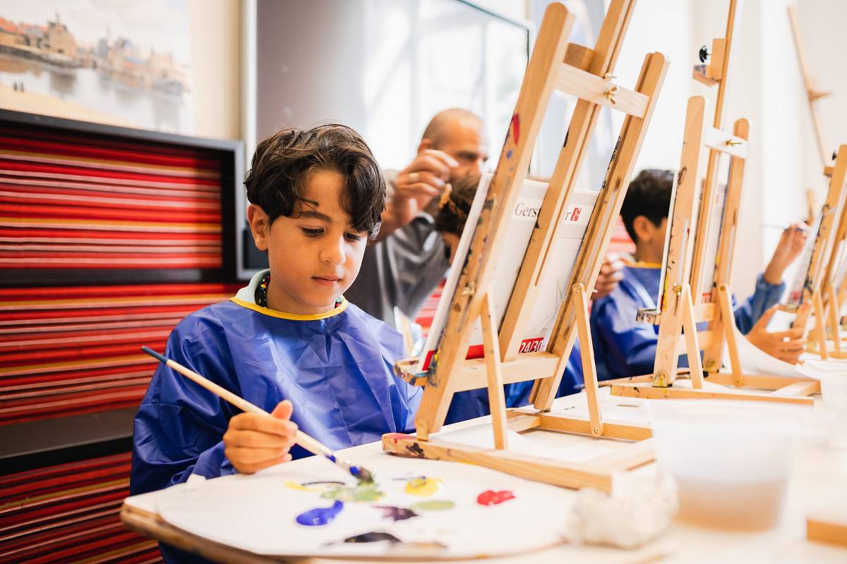Een jongen schildert in de Kunstwerkplaats tijdens een workshop van Hallo Vermeer in het Mauritshuis.