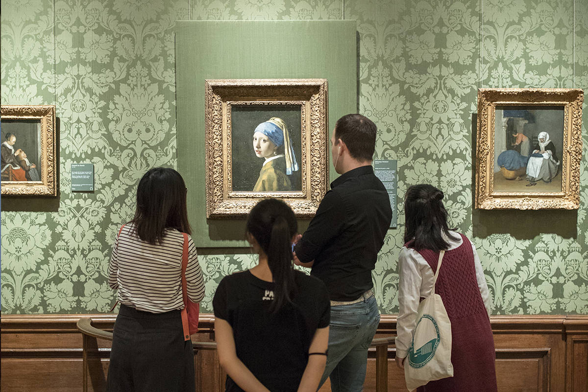 We zien verschillende personen staan bij Vermeer's 'Meisje met de parel'