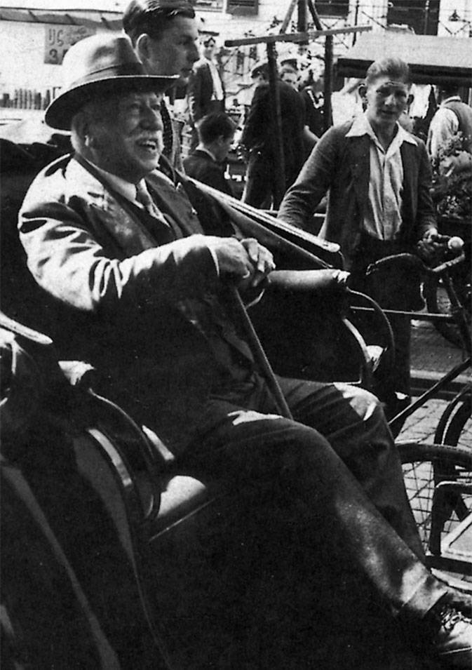  Mauritshuisdirecteur Abraham Bredius in een rijtuig. Hij draagt een hoed en lacht.