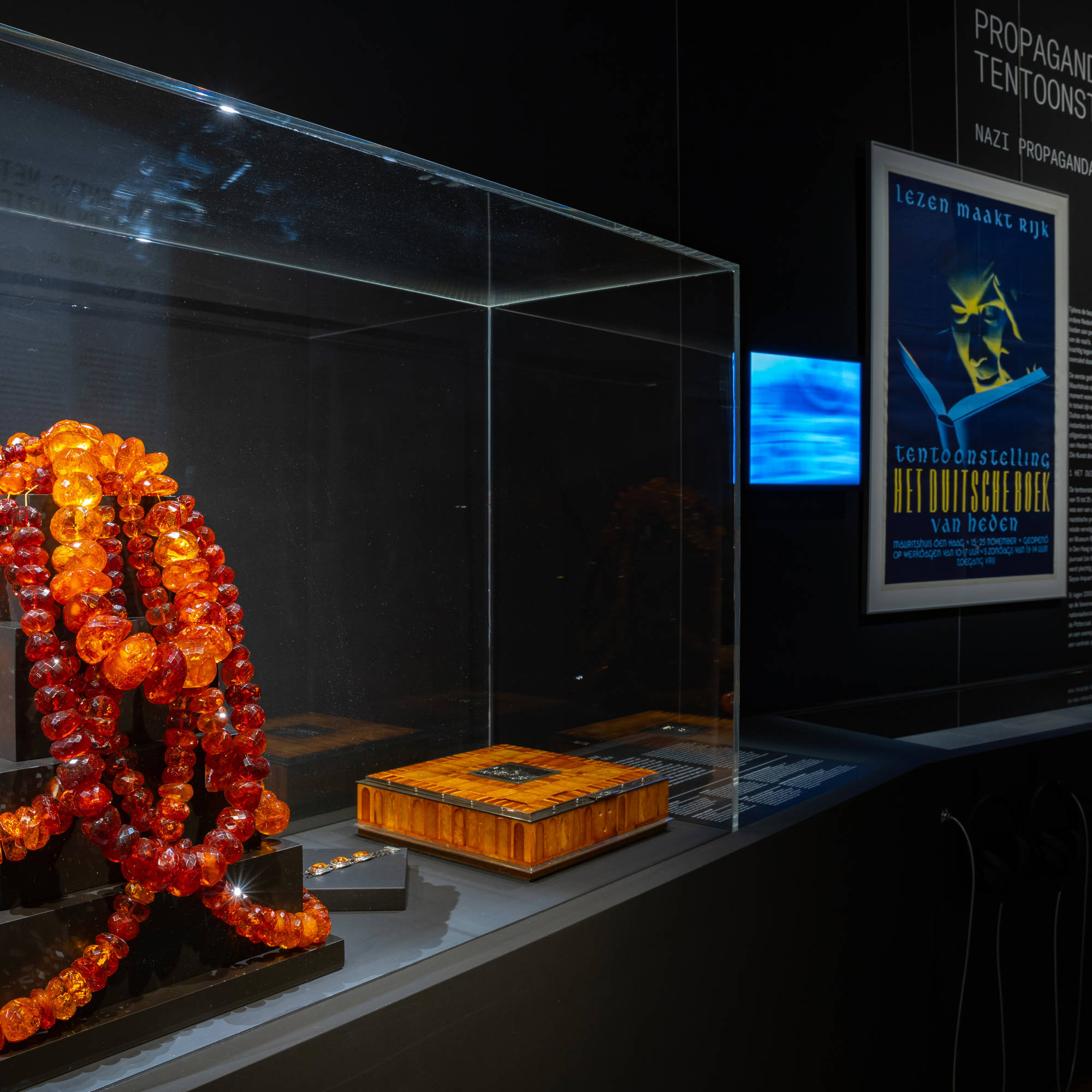 De tentoonstellingszaal van Huis in de Storm in het Mauritshuis, Den Haag. Er ligt een grote oranje ketting en er hangt een propagandaposter.