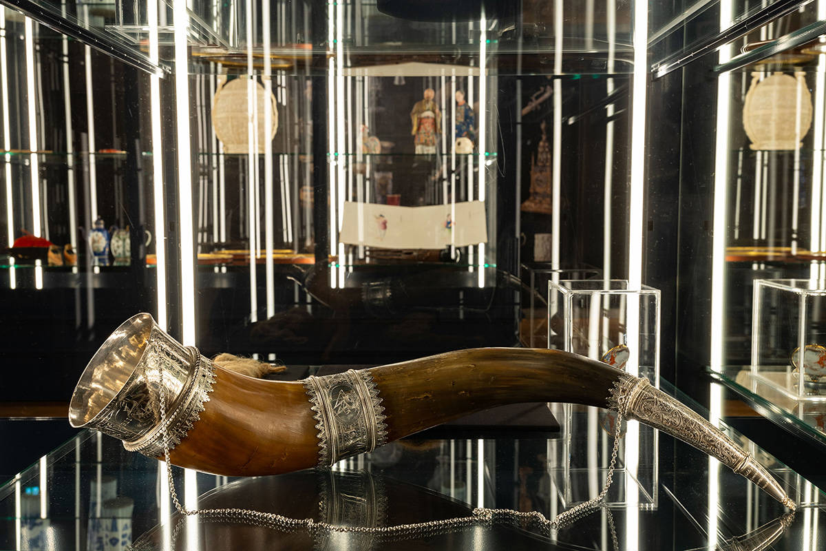 Zaalfoto van tentoonstelling Verdwenen Museum. We zien een houten hoorn met zilveren versieringen en een kettinkje.