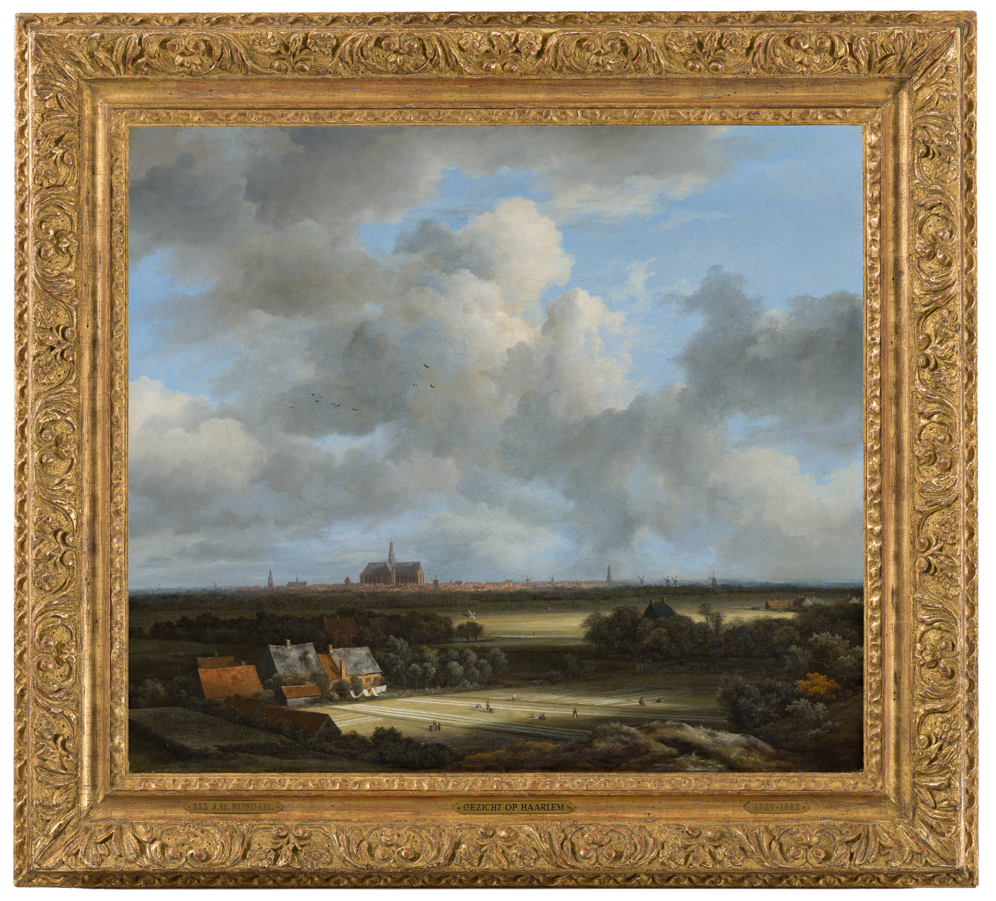 Ingelijst schilderij van Jacob van Ruisdael. Je ziet Gezicht op Haarlem met bleekvelden in een rijk versierde goudkleurige lijst.