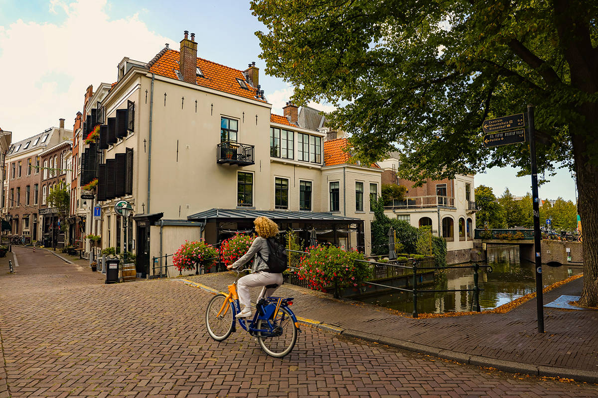 Fietser steekt bruggetje over versiert met bloemen aan de Denneweg in Den Haag op loopafstand van het Mauritshuis