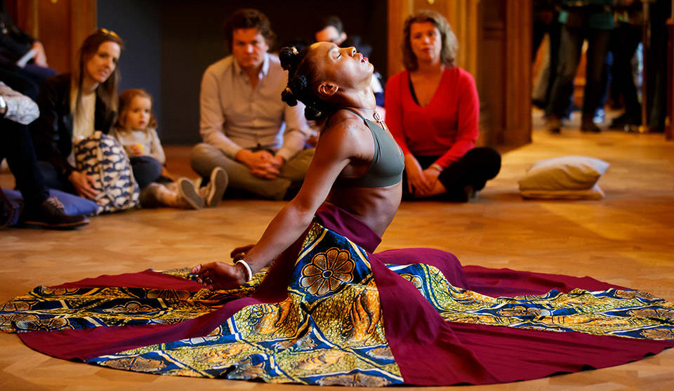 Een danseres knielt in het midden van een kring in het Mauritshuis, Den Haag.