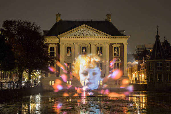 Je ziet een lichtprojectie op het Mauritshuis in Den Haag. Het is verder donker.