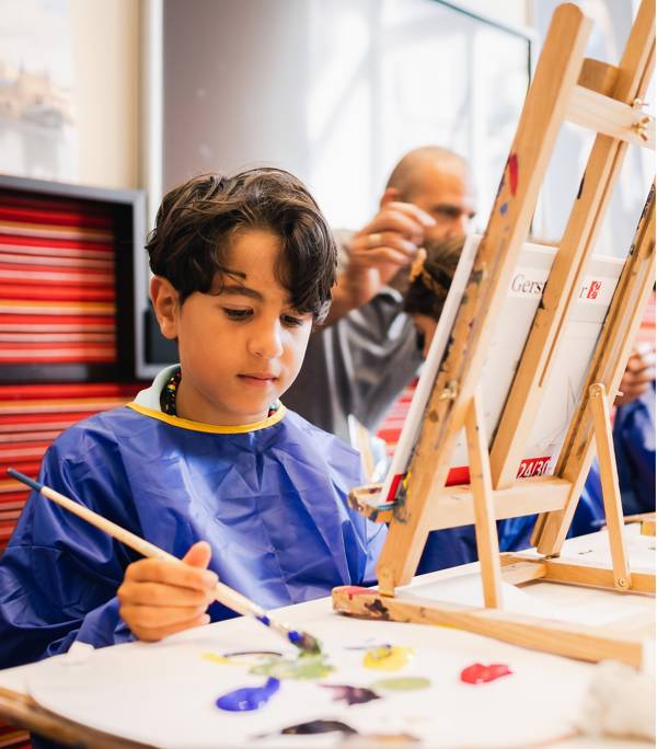 Een jongen schildert in de Kunstwerkplaats tijdens een workshop van Hallo Vermeer in het Mauritshuis.