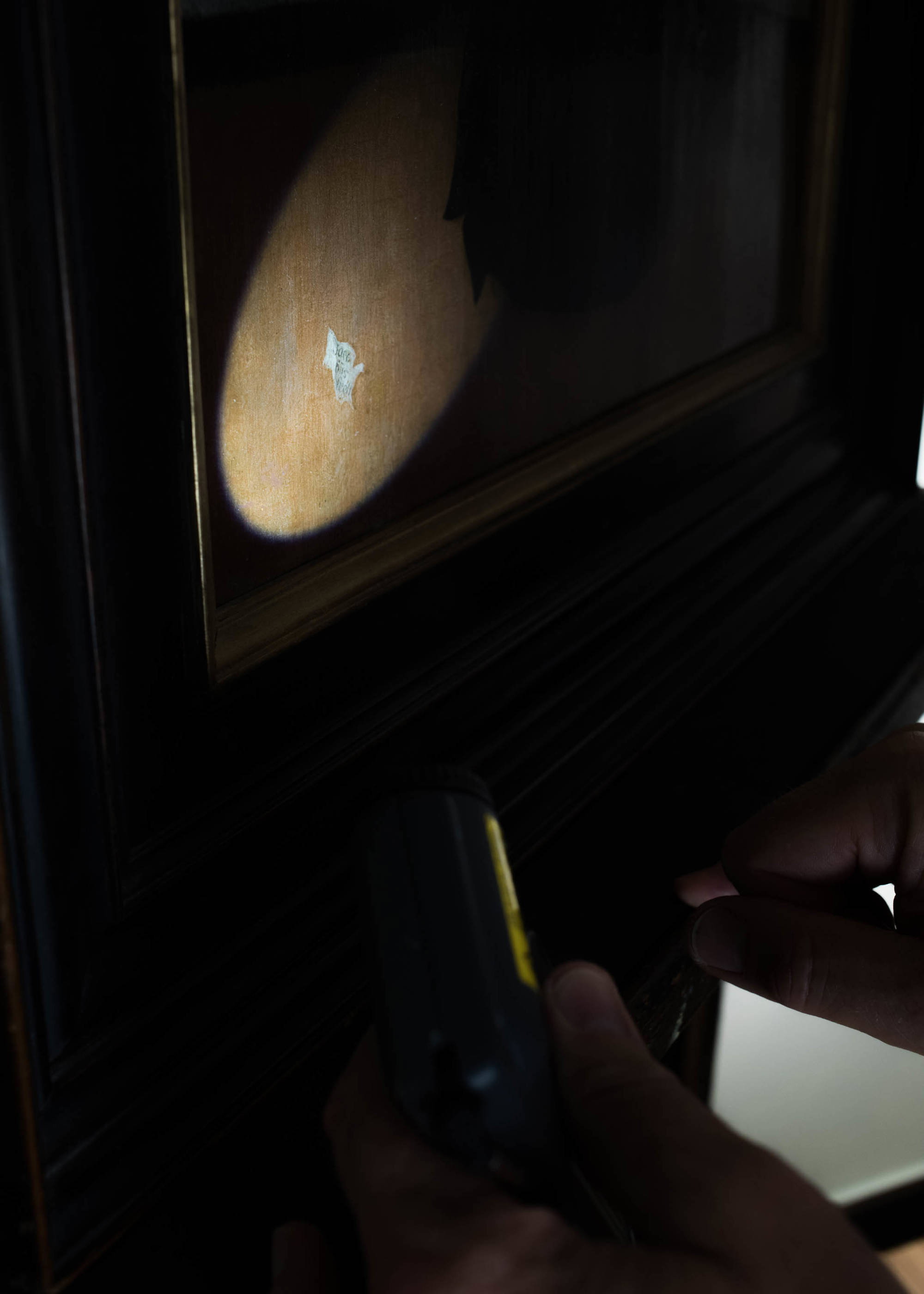 Detail van Vrels handtekening op het schilderij Interieur met lezende oude vrouw, met een jongen achter het raam.