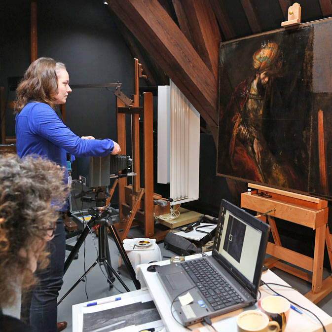 Een foto van een onderzoeker die een foto maakt van het doek Saul en David van Rembrandt.