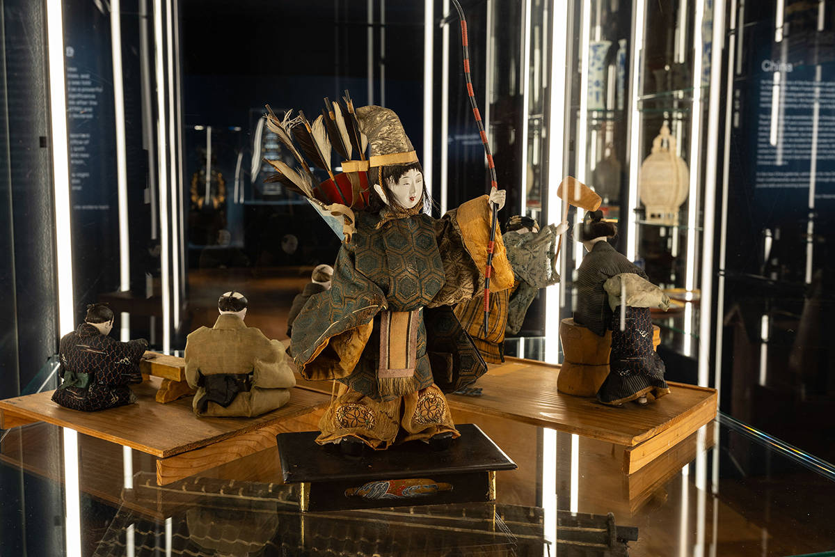 Een foto van de zaal van de tentoonstelling het Verdwenen Museum. We zien een pop in klederdracht met een boog.