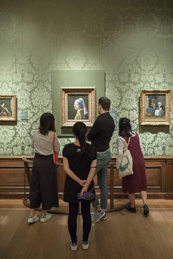 Visitors of the museum look at Vermeers Girl With A Pearl Earring at Museum Mauritshuis in The Hague.