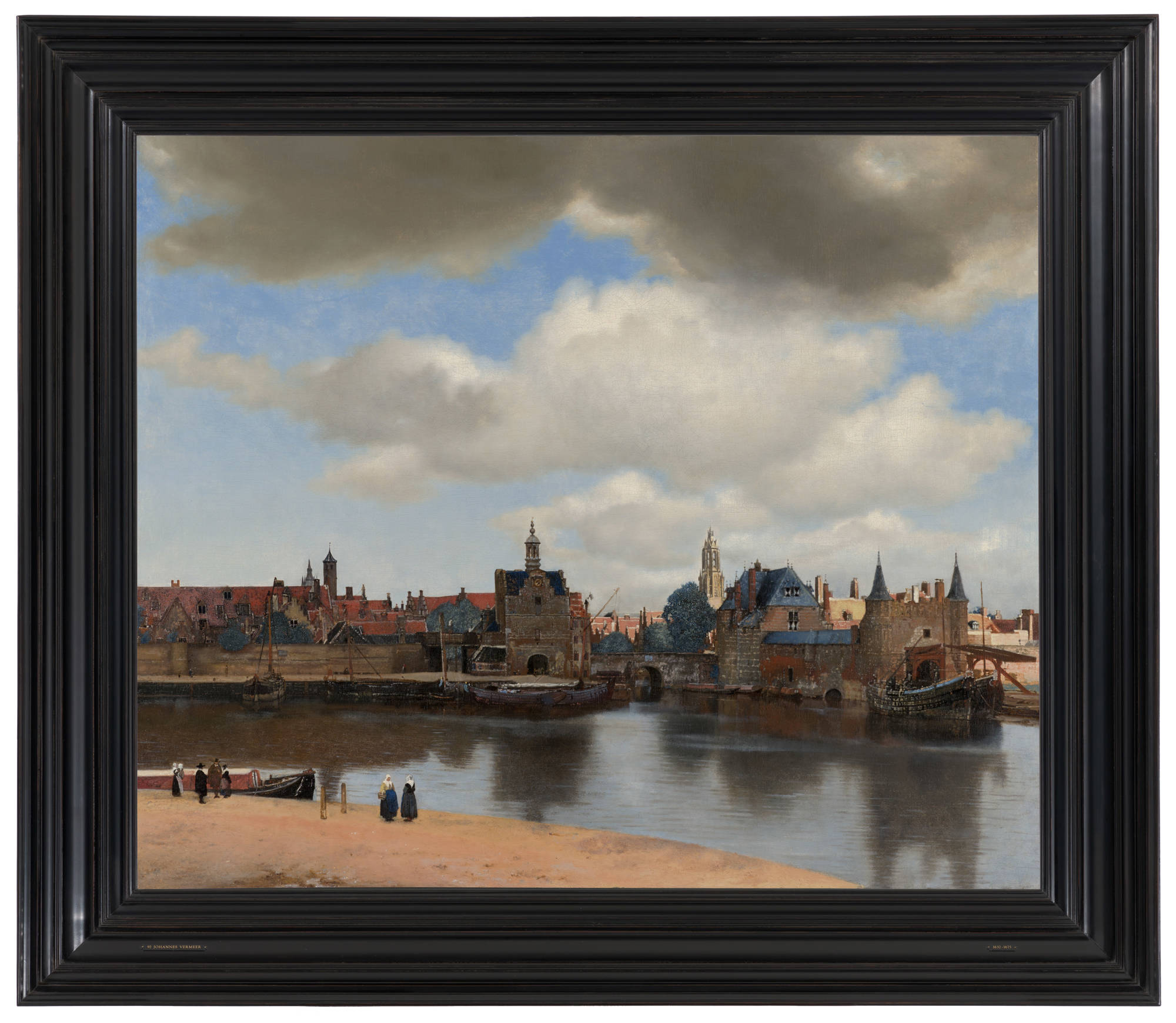 Ingelijst schilderij van Johannes Vermeer. Je ziet Gezicht op Delft in een donkere houten lijst. Framed painting by Johannes Vermeer. You can see View of Delft in a dark wooden frame.