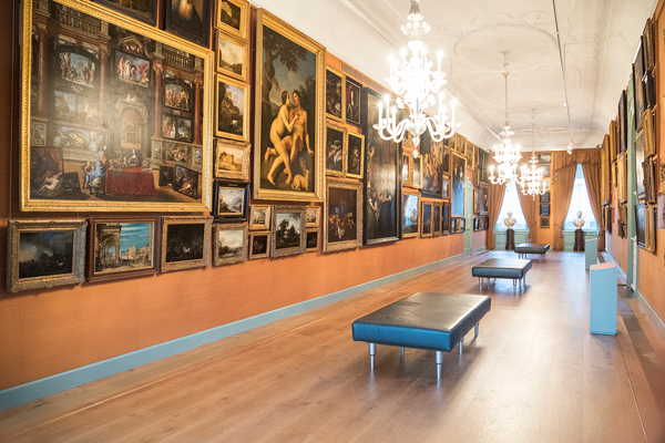 Een overzichtsfoto van Galerij Prins Willem V. De wanden hangen van plint tot plafond vol schilderijen uit de 17e eeuw.