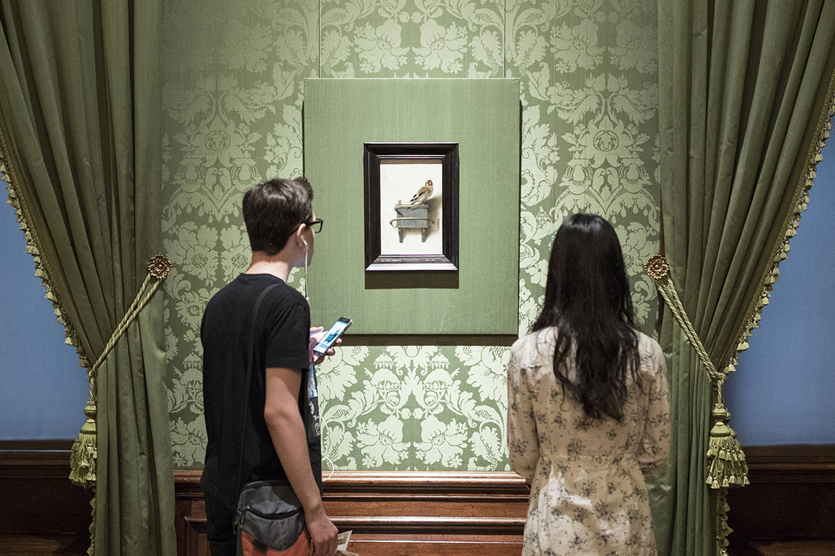 Visitors enjoy The Goldfinch by Fabritius at museum Mauritshuis in The Hague.
