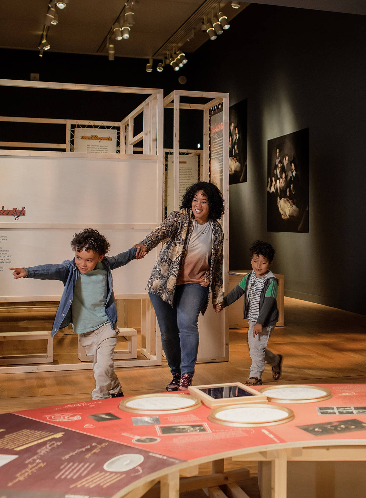 Een moeder en haar kinderen bekijken een tentoonstelling in het Mauritshuis.