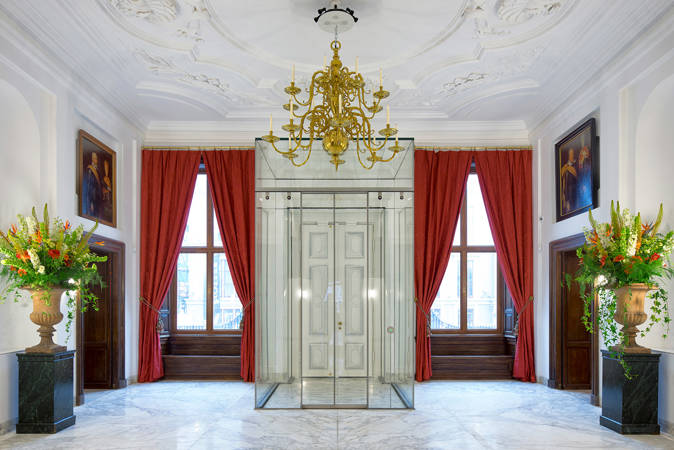 Zaal 1 van het Mauritshuis heeft een glazen lift en een kroonluchter. Dit is de voormalige entree van het museum.