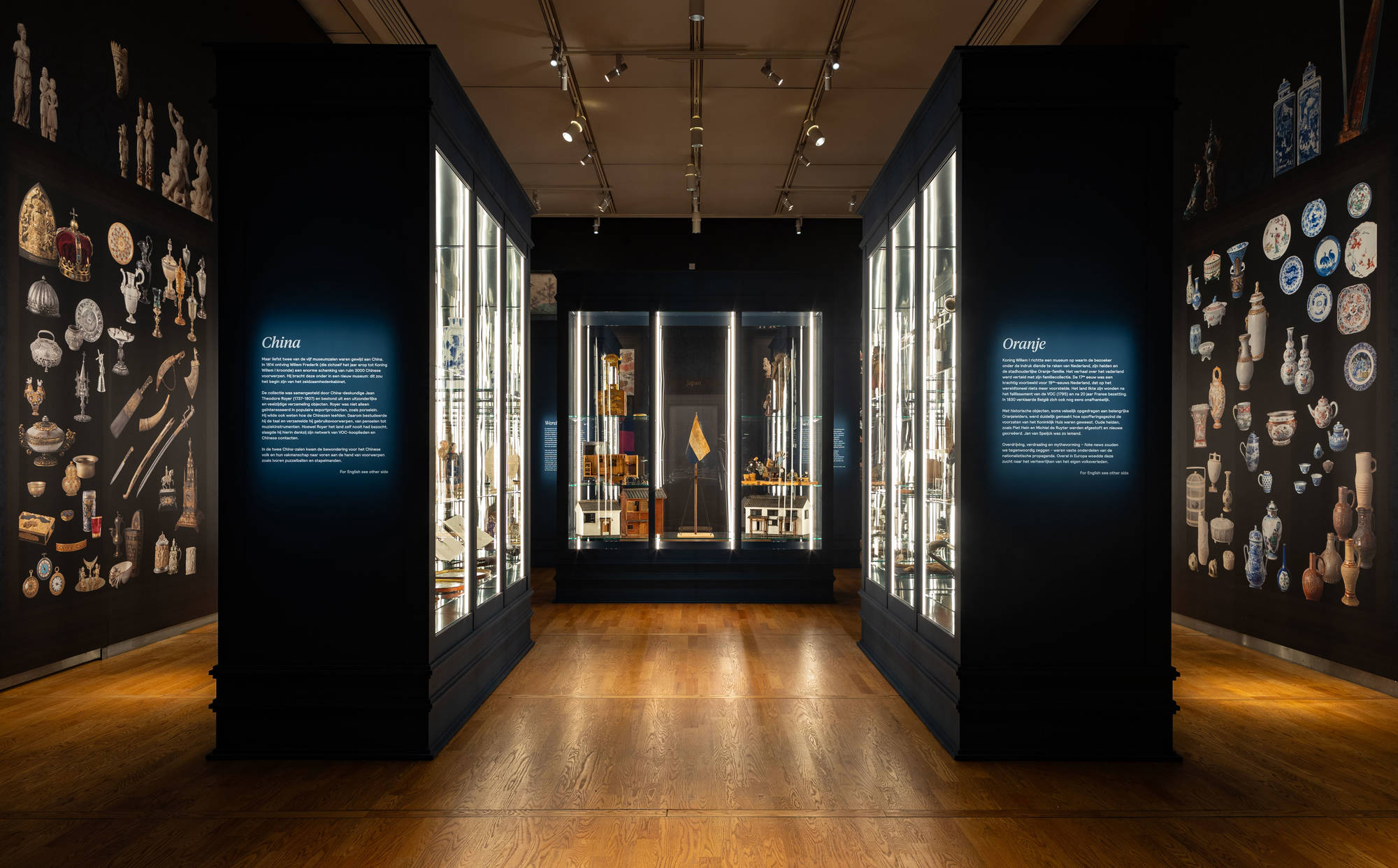 De tentoonstellingszaal met allemaal vitrines waarin bijzondere voorwerpen liggen of staan. We zien de woorden 'China' en 'Oranje' op twee bordjes staan.