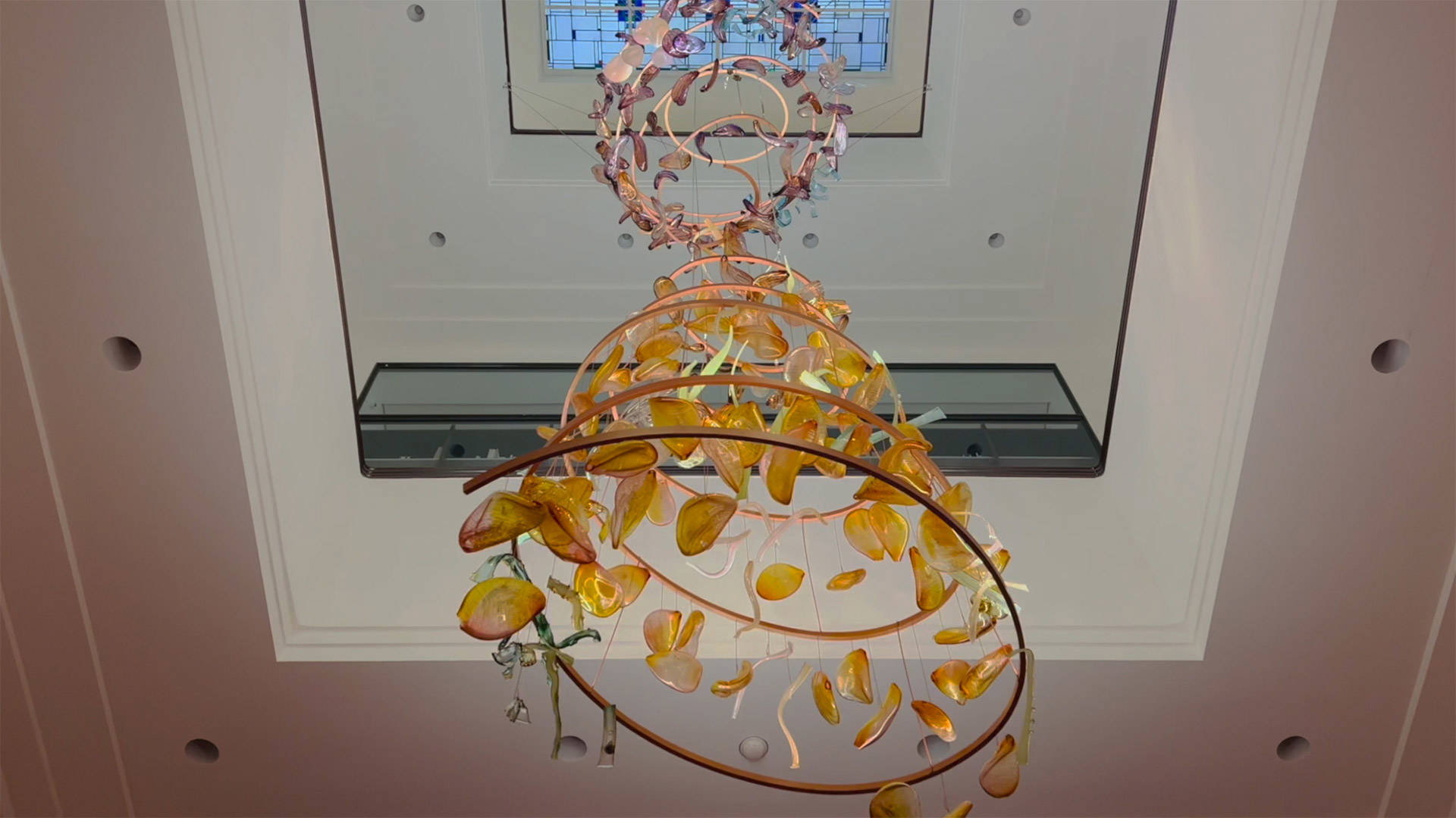 Glaskunst van Bibi Kunst hangt in het atrium van het Mauritshuis. Het bestaat uit prachtig gekleurde glasstukken die samen een wervelwind vormen.