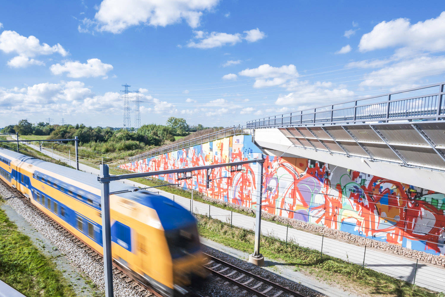 Een trein rijdt langs de mural van ONUR 2, geinspireerd door museum De Fundatie en kasteel Het Nijenhuis.