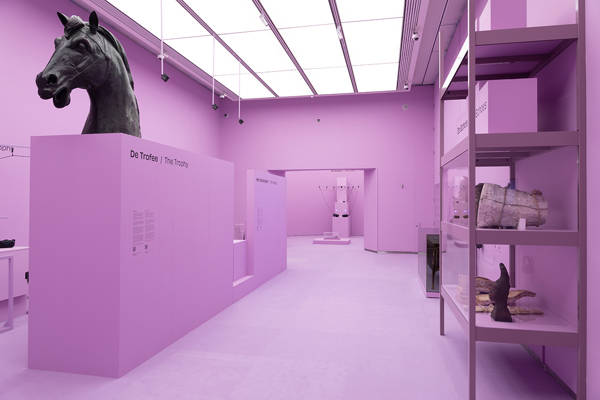 Een zaalfoto van de toonstelling Roofkunst. De zaal is helemaal roze, rechts zie je de bronzen kop van een paard. Er staat: de trofee.