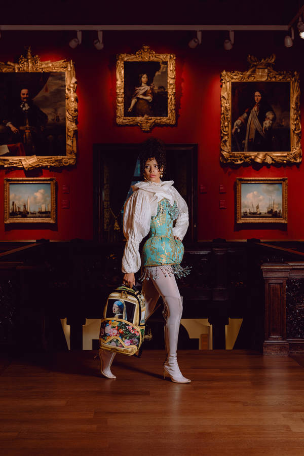 Een model poseert in de trapzaal van het Mauritshuis met een tas van Sprayground.