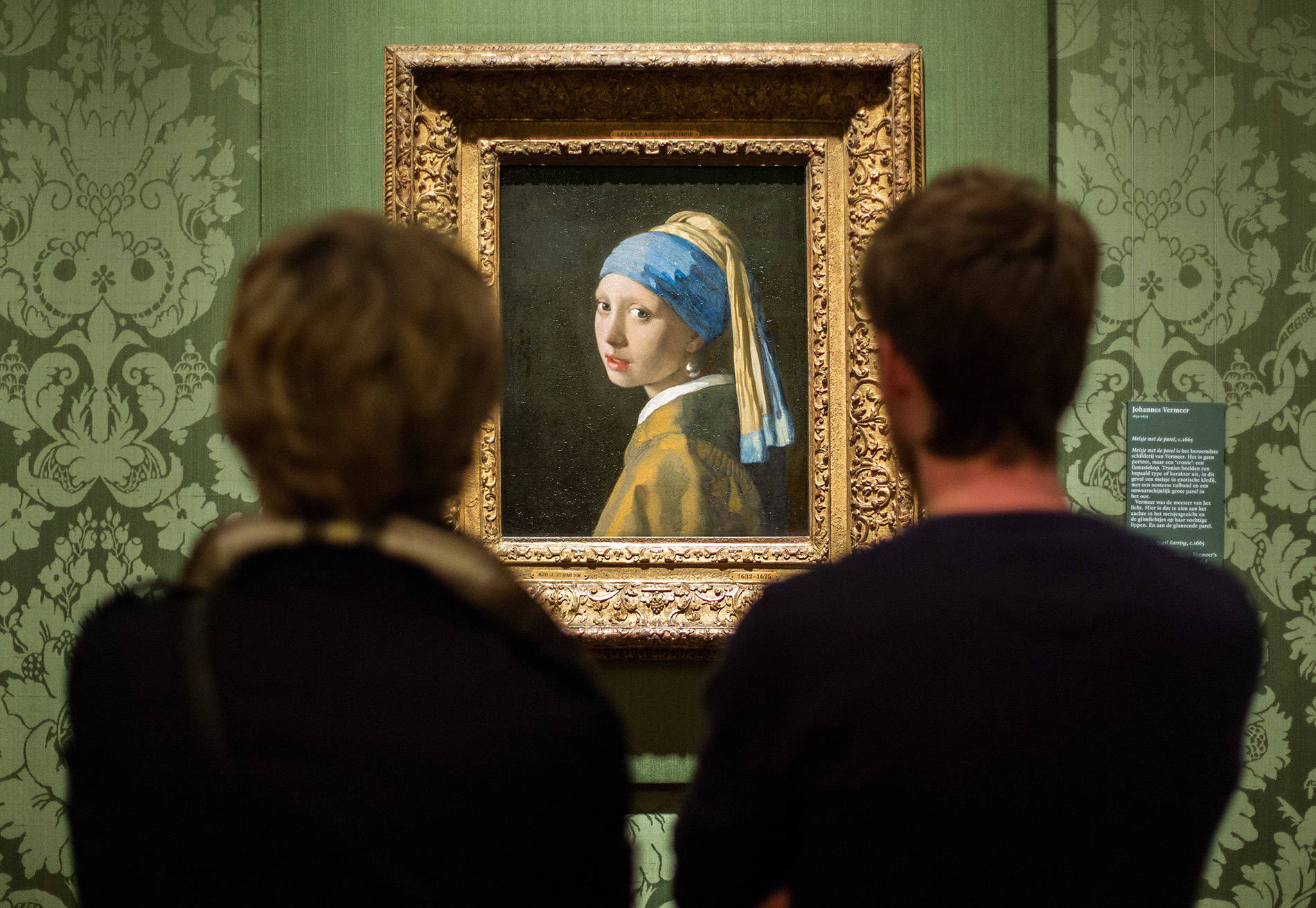 Achteraanzicht van twee bezoekers die kijken naar Meisje met de Parel van Vermeer.