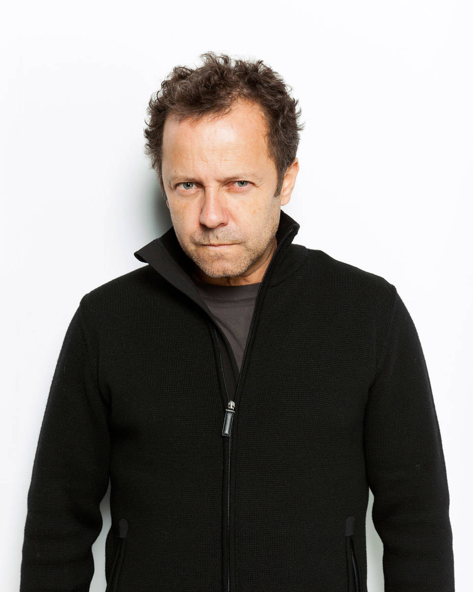 Kunstenaar Vik Muniz, hij draagt een zwarte trui en kijkt strak in de camera