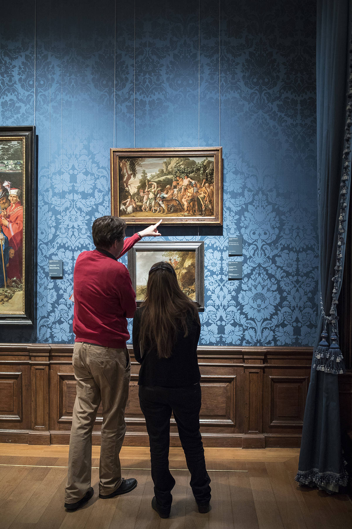 Twee bezoekers kijken naar een schilderij in het Mauritshuis in Den Haag.
