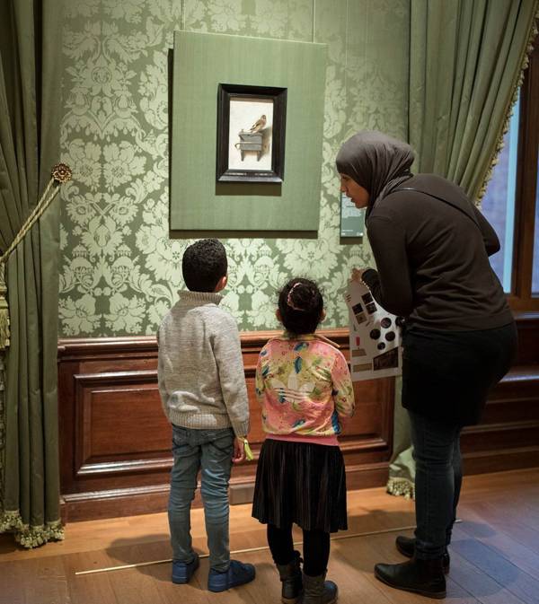 Een moeder bekijkt samen met haar kinderen het Puttertje in het Mauritshuis in Den Haag.