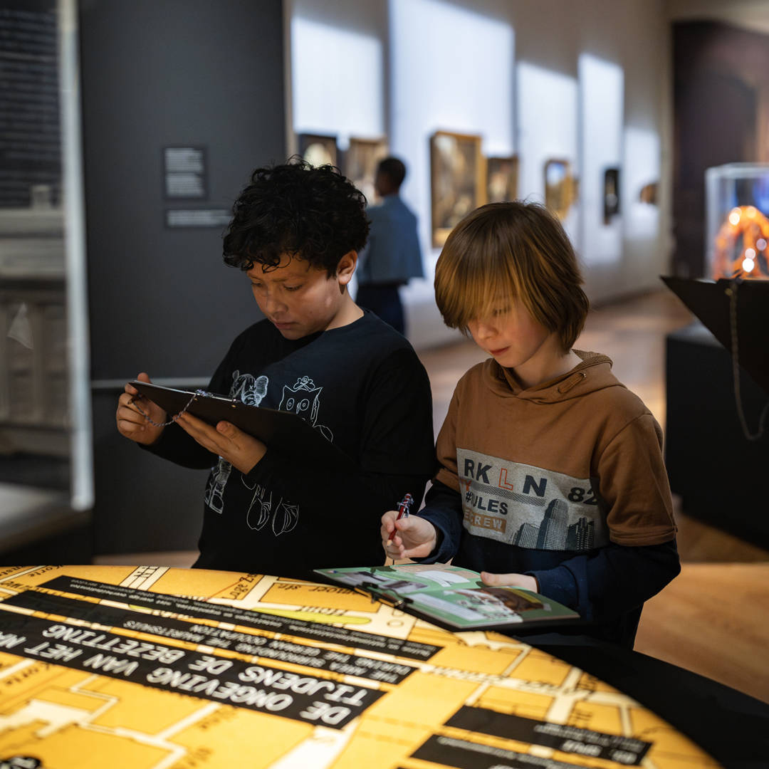 Kinderen maken met een logboek opdrachten bij de tentoonstelling Huis in de Storm.