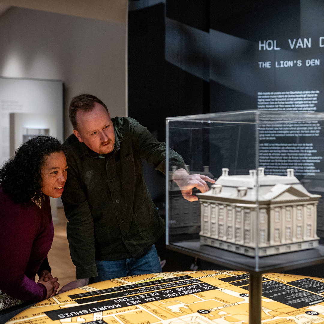 Twee vrienden kijken naar de replica van het Mauritshuis in de tentoonstellingszaal.