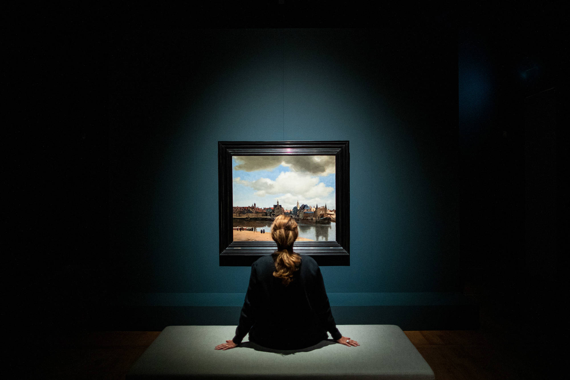 Een bezoeker kijkt in het donker naar Gezicht op Delft van Johannes Vermeer in het Mauritshuis.