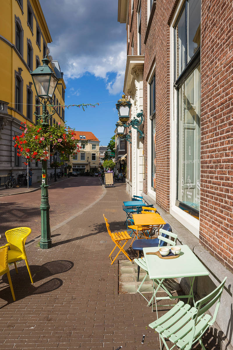 Je kijkt het gezellige pittoreske winkelstaatje de Dennenweg in vanaf Hotel Des Indes, met een koffietentje op de voorgrond
