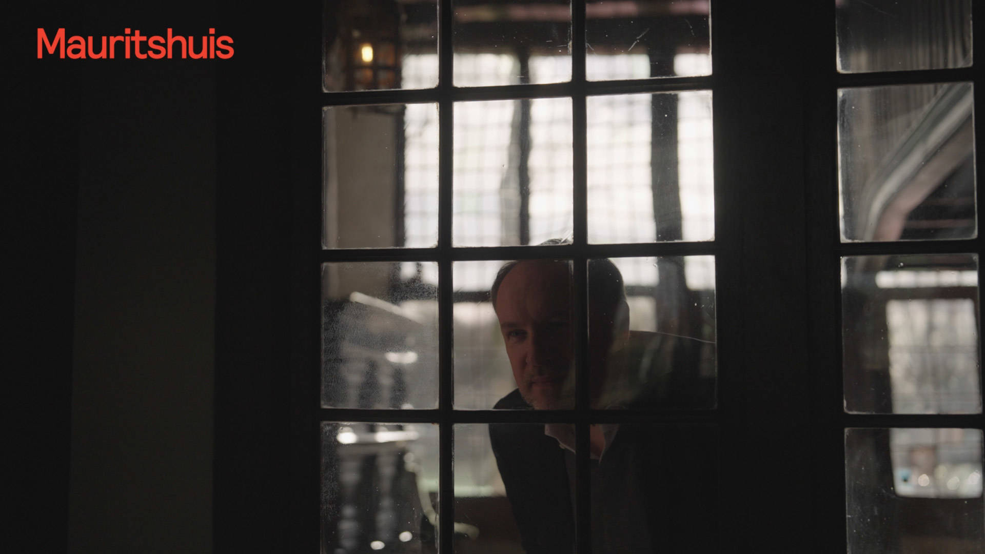 Curator Quinten Buvelot van het Mauritshuis kijkt door het raam.