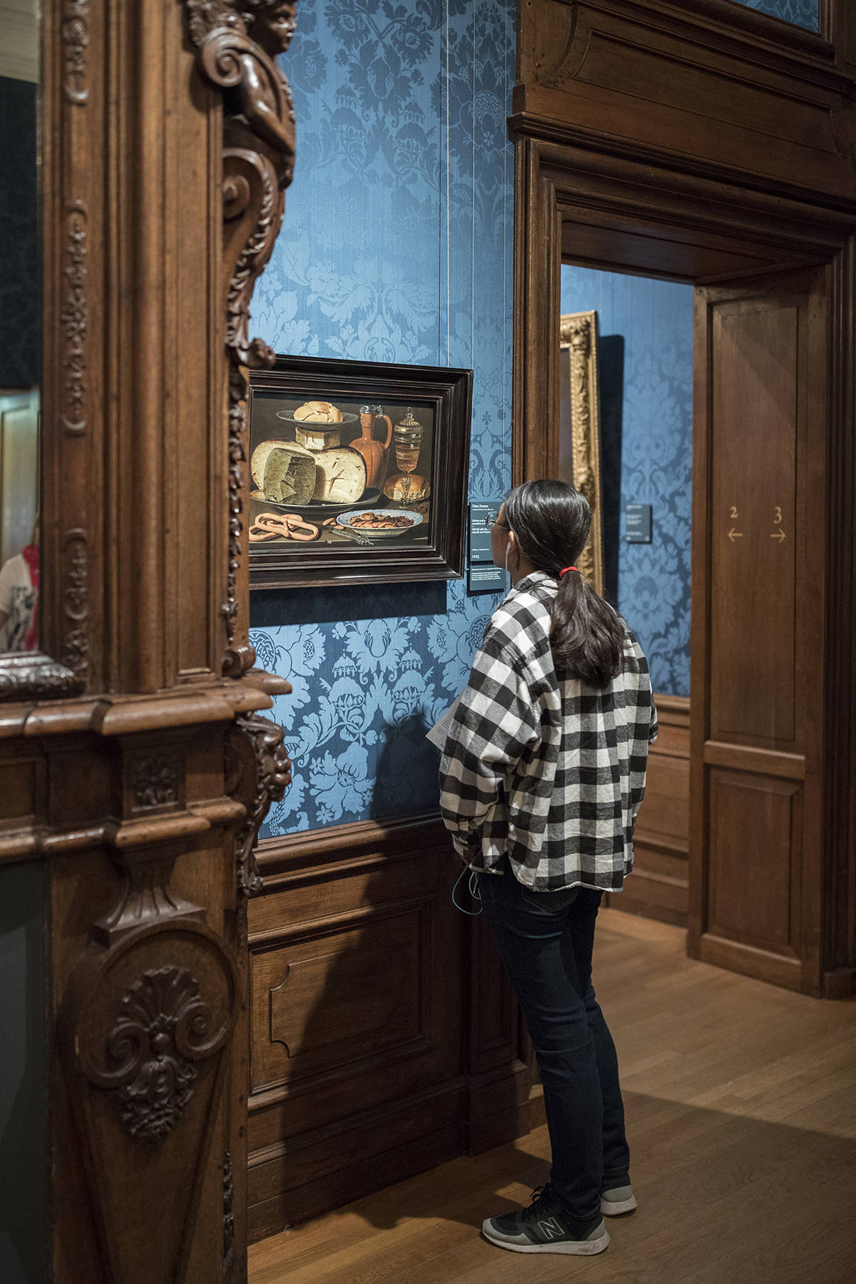 Een meisje kijkt naar het Stilleven Met Kazen Amandelen En Krakelingen van Clara Peeters in het Mauritshuis Den Haag.